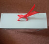 The box is light/mint green and includes a red ribbon on top.